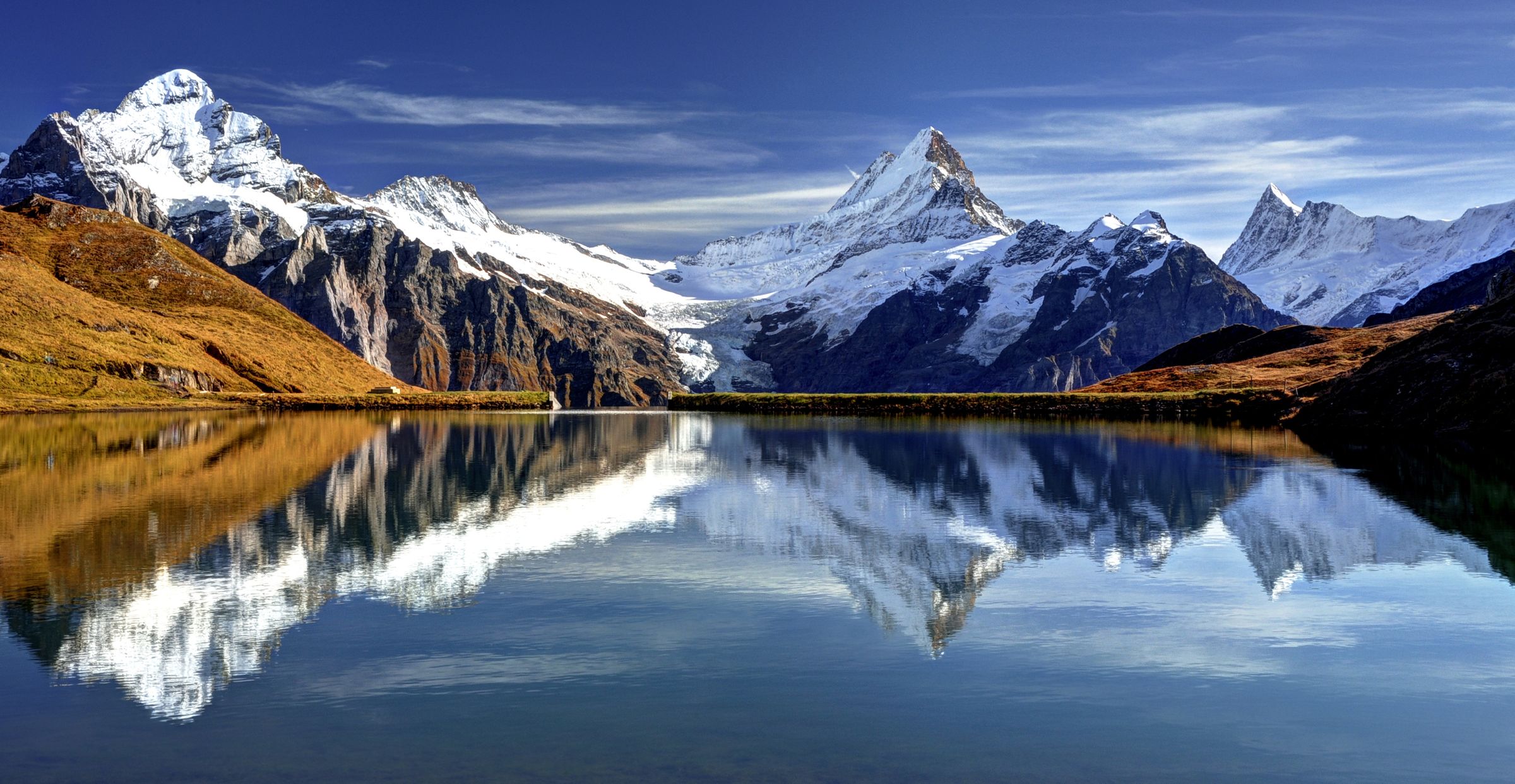 Schneebedeckte Berggipfel spiegeln sich in einem Bergsee
